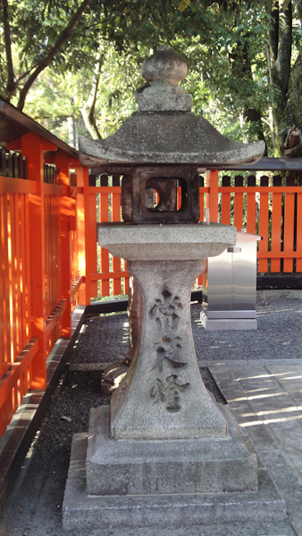 a stone lantern surrounded by a vermillian orange and black fence